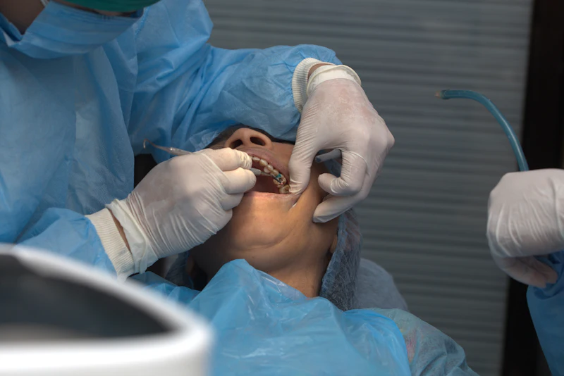 A dentist in gloves and a surgical gown working in a patient's mouth