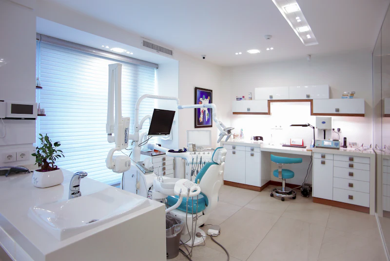 A bright, modern dental treatment room with a chair, light and cabinets